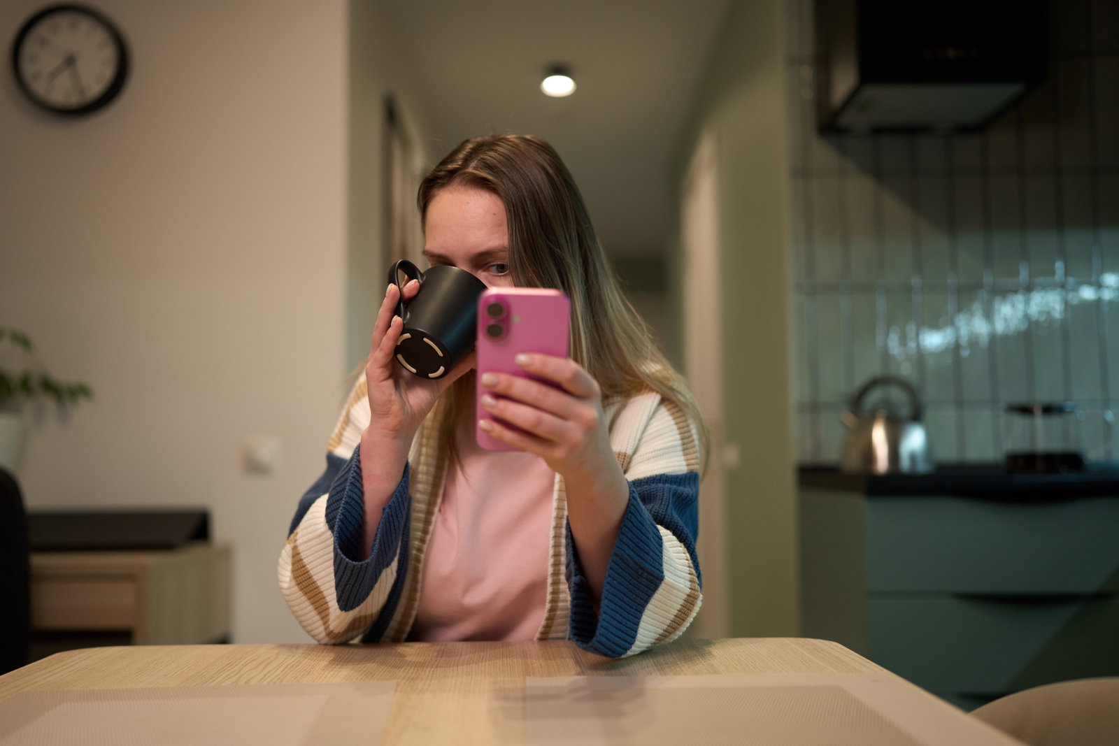 Fokus auf dem Handy, Frau trinkt Cafe und starrt dabei aufs Handy